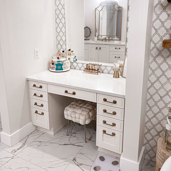After photo of bathroom makeup vanity with white cabinets, white quartz countertop, and porcelain floor tile that looks like white & gray marble.