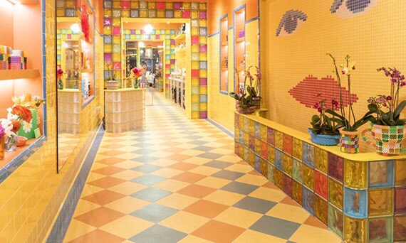 Susan Alexandra accessory store in New York with bright yellow wall tile with bright blue trim, yellow, blue, green, and orange checkerboard floor tile.