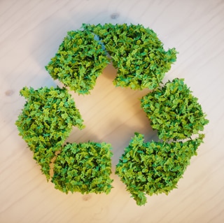 Recycling symbol made of leaf clusters laying on wooden surface.
