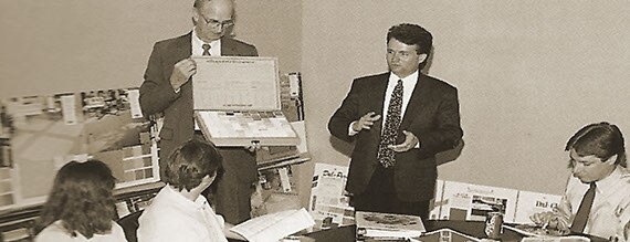 Black and white photo of a conference room of women and men in suits and ties.