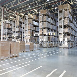Large warehouse with pallets of tile wrapped in plastic stacked on 50-foot tall shelves.