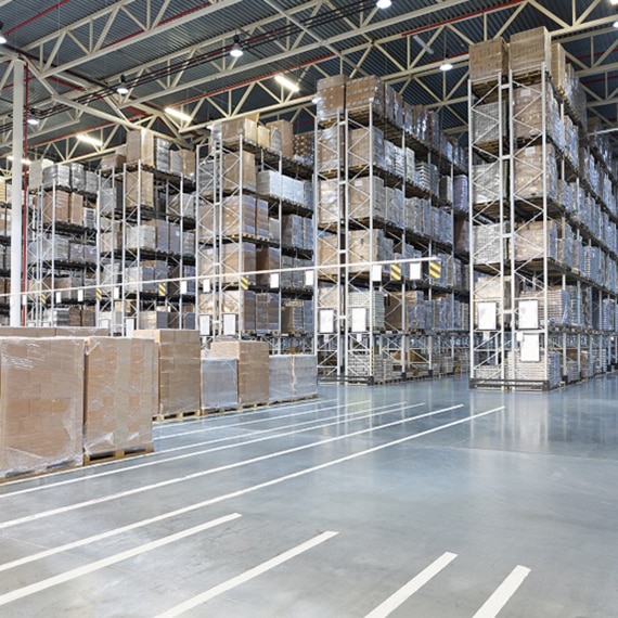 Large warehouse with pallets of tile wrapped in plastic stacked on 50-foot tall shelves.