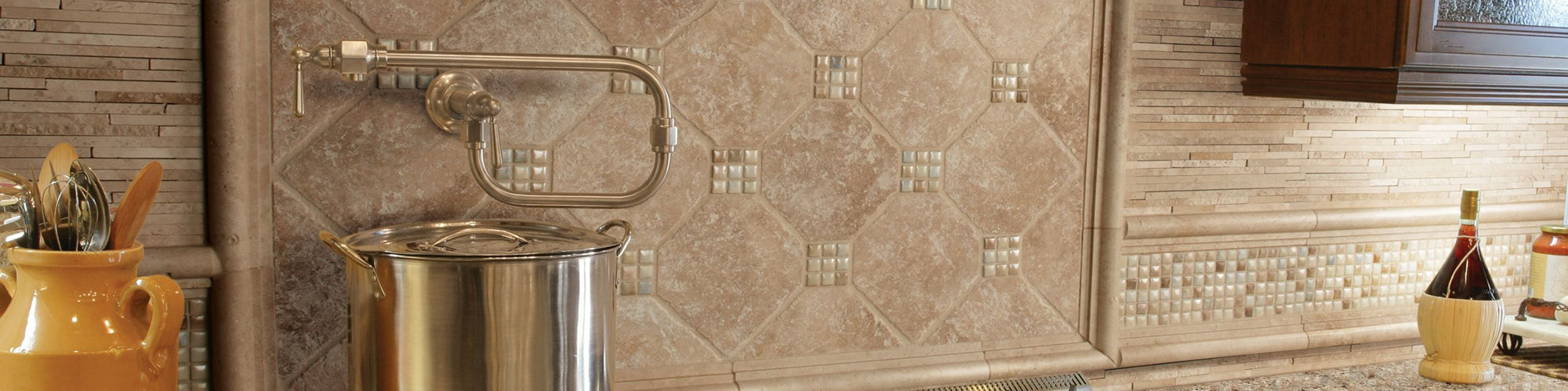 Kitchen backsplash with tan travertine decorative backsplash with mosaic accents, potholder, and brown & beige granite countertop.