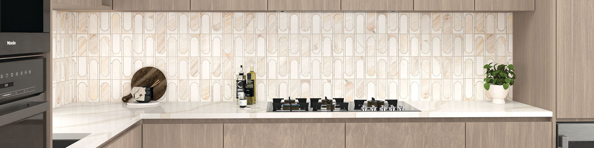 Kitchen backsplash of pre-cut beige marble and white marble mosaic tile, off-white quartz countertop, woodgrain upper & lower cabinets.