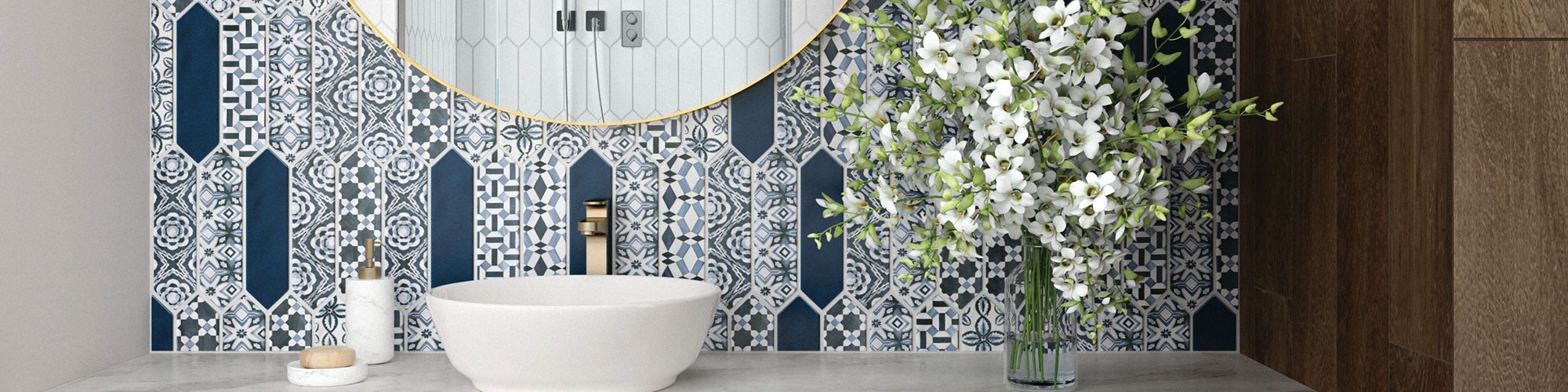 Bathroom vanity with gray marble look countertop of porcelain slab, blue & white encaustic picket tile backsplash, vessel sink, and round mirror.