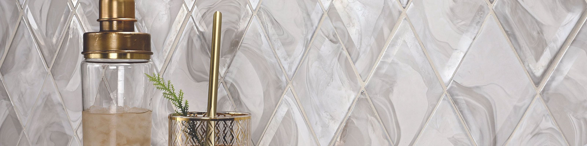 Dry bar with white & gray diamond-shaped backsplash, gold trimmed hi-ball glass and shaker.