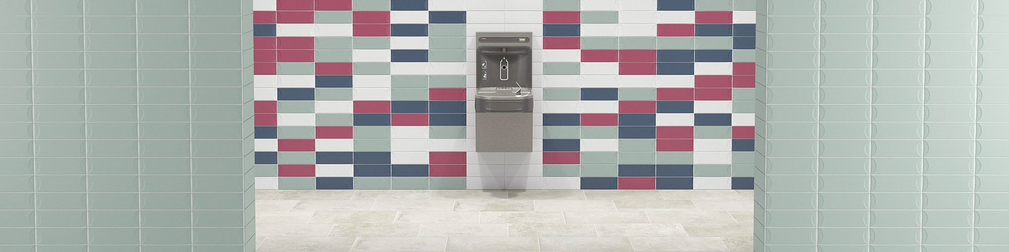 School restroom with beige slip-resistant floor tile with antimicrobial properties, mint green wall tile, water fountain mounted on wall with blue, pink, and mint tile.