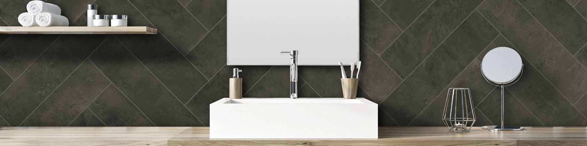 Bathroom backsplash of charcoal gray wall tile in a herringbone pattern with mirror and floating shelf, white vessel sink on floating natural wood vanity.