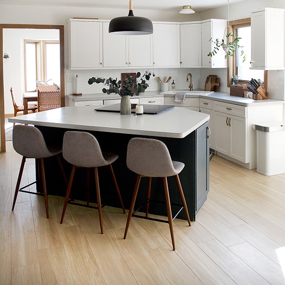 Angled kitchen with triangluar island and light wood look plank tiles on the floor