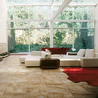 Beautiful open living area with large windows big sofas and veined stone look tile 
