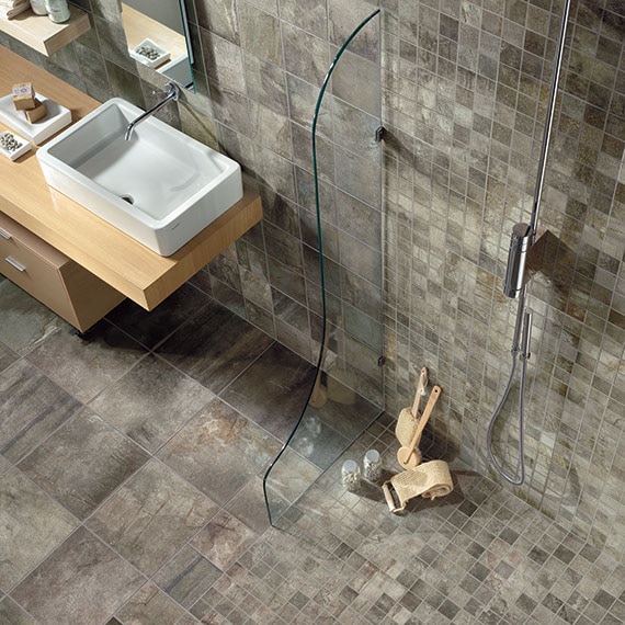 Close up of zero entry shower floor in gray stone look tile in two sizes: a mosaic and 12 by 12 on the bathroom floor