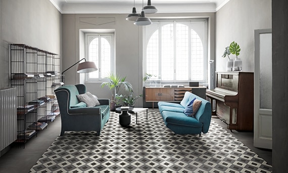 Living room with white, gray and black encaustic floor tile, teal sofas, upright piano, and arched picture window.